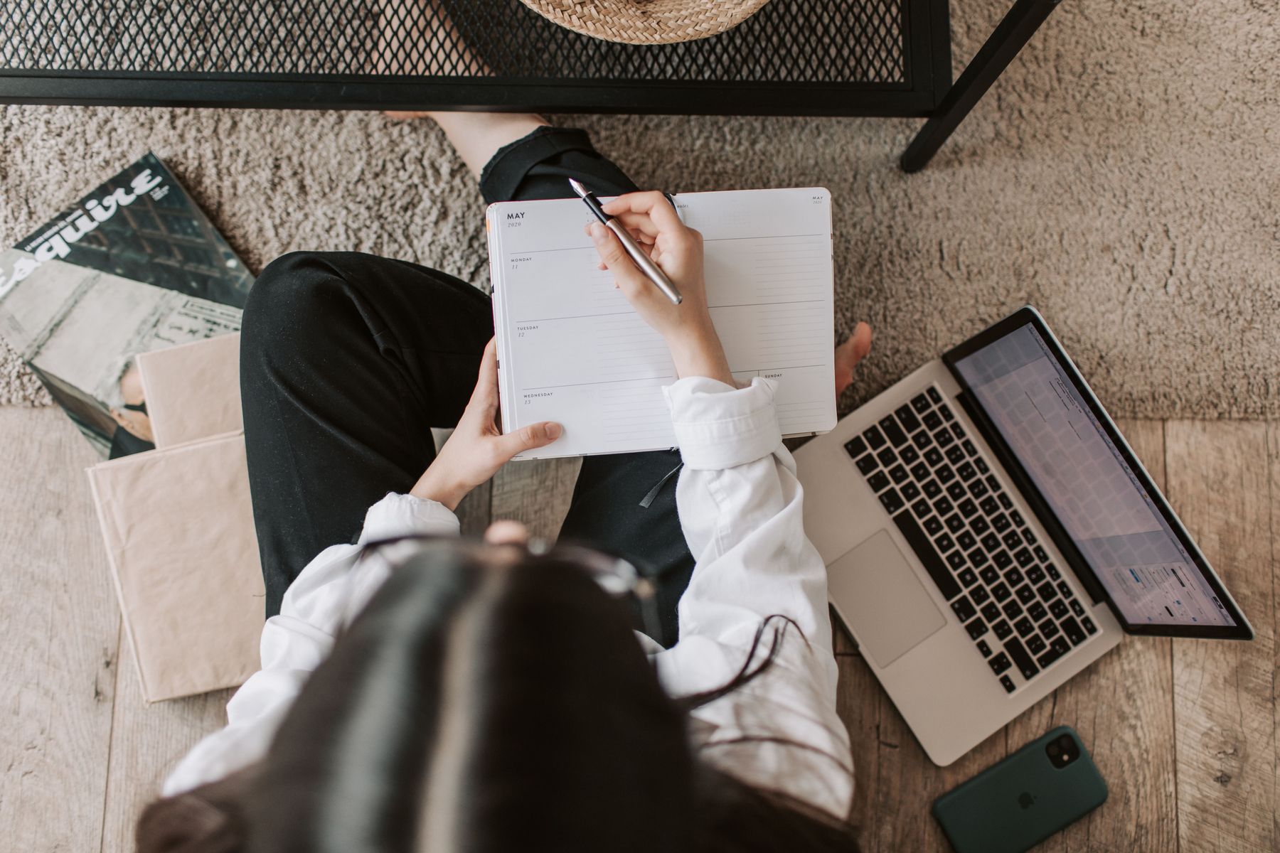 A woman writing in a notebook beside her laptop